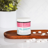 Oral probiotics in raspberry lemonade flavor by Wellnesse, with white tablets scattered on a wooden tray.