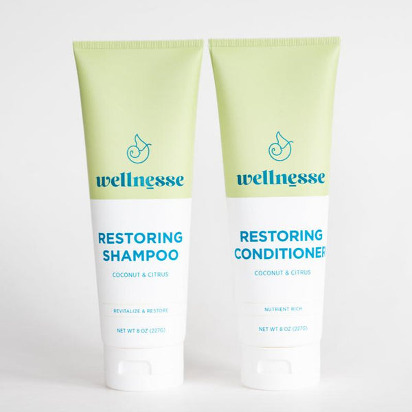 Wellnesse restoring shampoo and conditioner bottles styled together in a bathroom setting