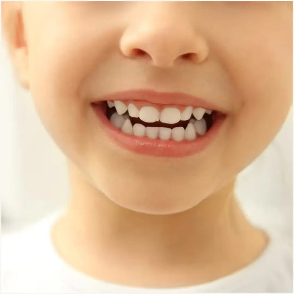 Smiling child showing clean teeth after brushing with Wellnesse vanilla toothpaste