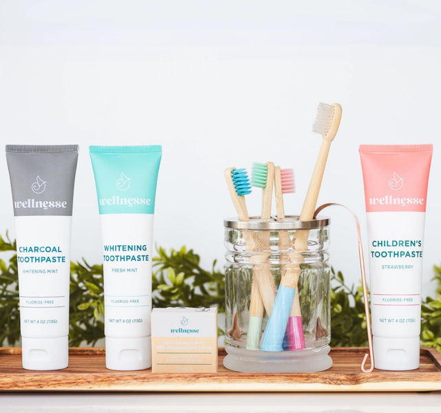 Wellnesse hydroxyapatite toothpaste varieties in strawberry, charcoal, and mint with toothbrushes and floss
