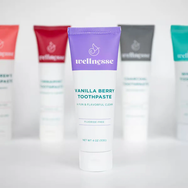 Wellnesse vanilla toothpaste purple tube in focus with the fluoride-free lineup blurred behind