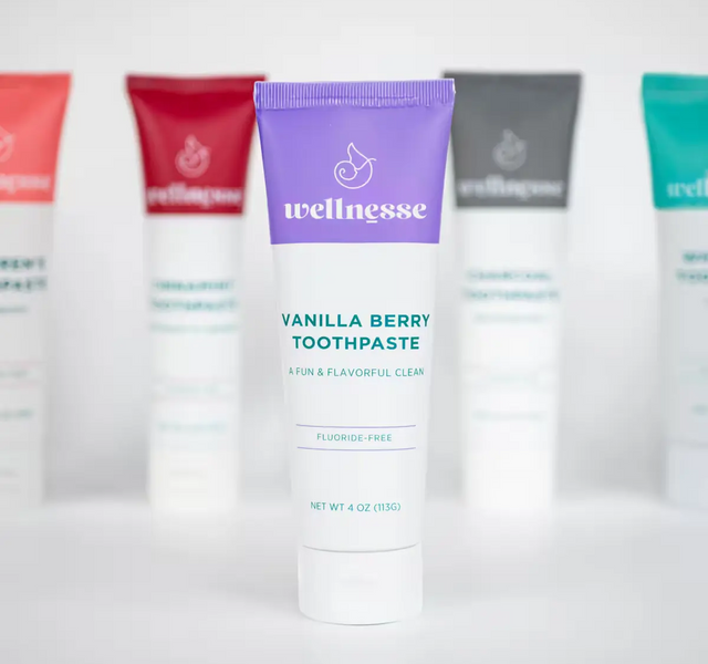 Wellnesse vanilla toothpaste purple tube in focus with the fluoride-free lineup blurred behind