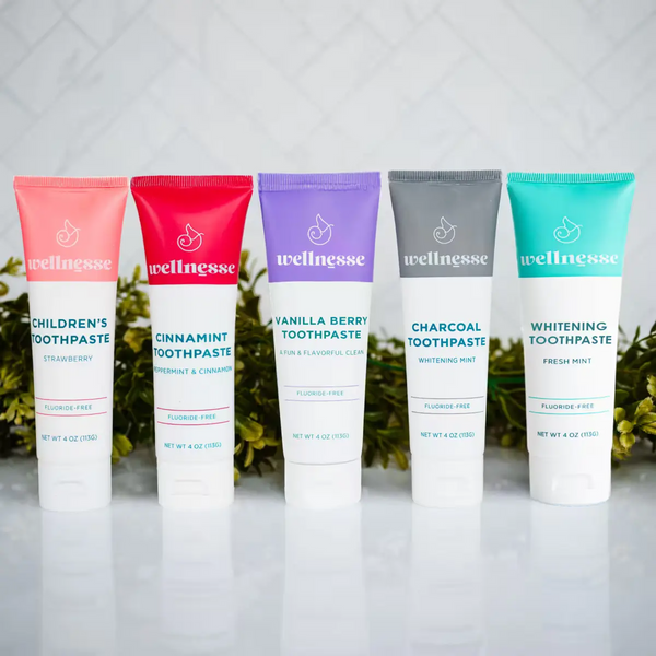Complete Wellnesse fluoride-free toothpaste lineup in all five flavors arranged against a white tile backdrop