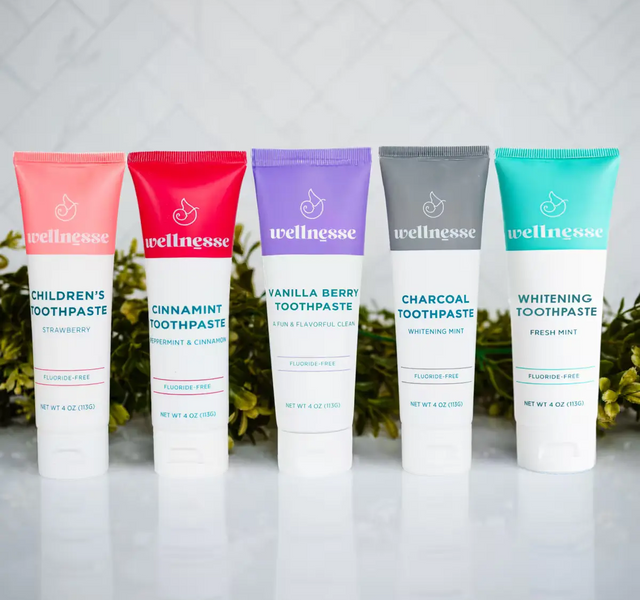 Complete Wellnesse fluoride-free toothpaste lineup in all five flavors arranged against a white tile backdrop