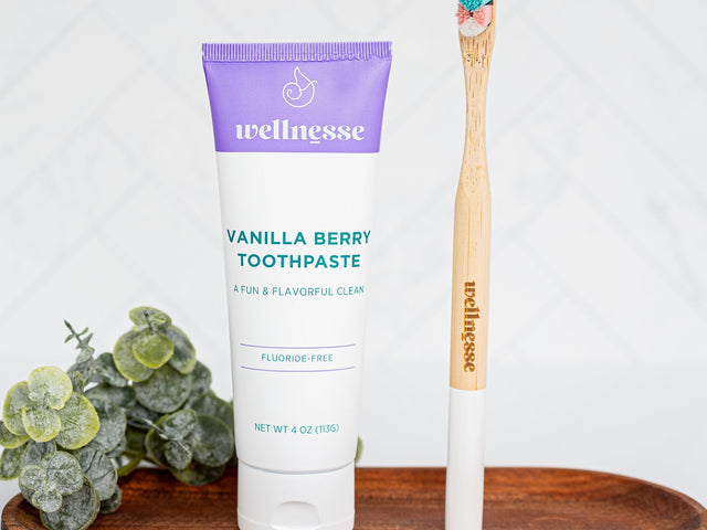Wellness toothpaste and wooden toothbrush on a wooden tray with a white background