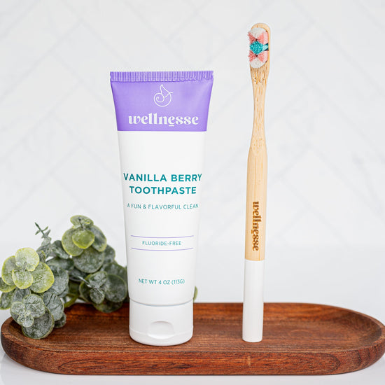 Wellness toothpaste and wooden toothbrush on a wooden tray with a white background