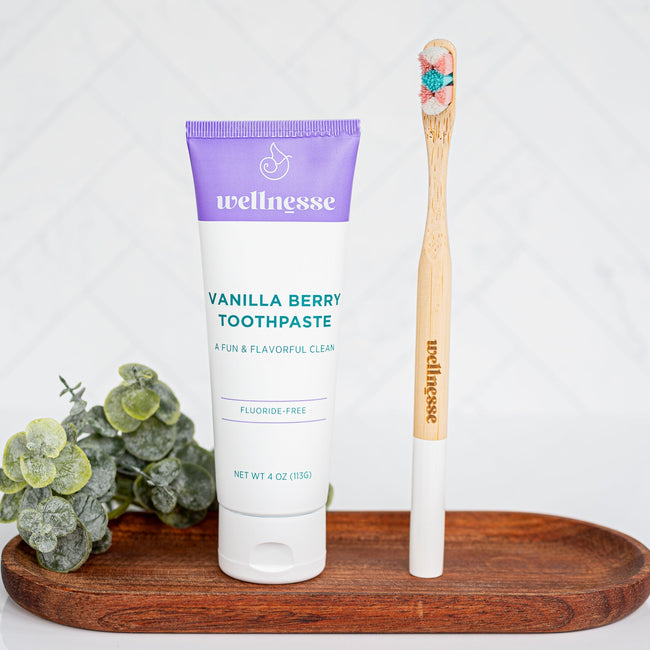 Wellness toothpaste and wooden toothbrush on a wooden tray with a white background