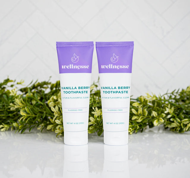 Two tubes of Wellnesse vanilla berry toothpaste with purple caps, fluoride-free for a fun and flavorful clean.