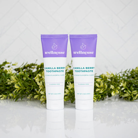 Two tubes of Wellnesse vanilla berry toothpaste with purple caps, fluoride-free for a fun and flavorful clean.