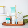Wellnesse mini gift set with whitening toothpaste, hand sanitizer, bamboo toothbrush, and floss on a tray