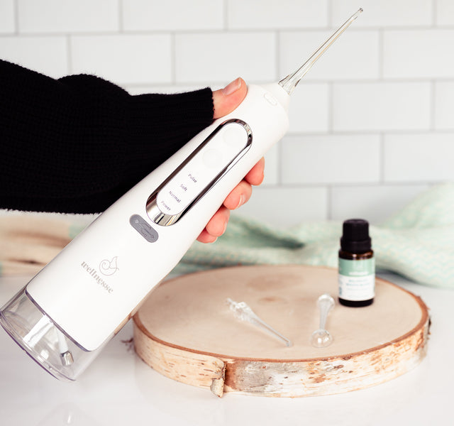 Close-up of the Wellnesse water flosser nozzle tip and pressure control dial in use