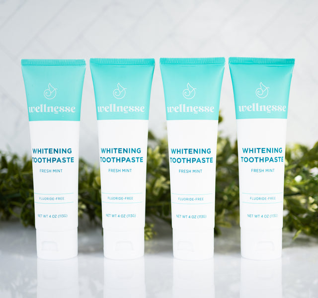 Natural teeth whitening toothpaste in fresh mint flavor, fluoride-free and displayed in a pack of four by Wellnesse.